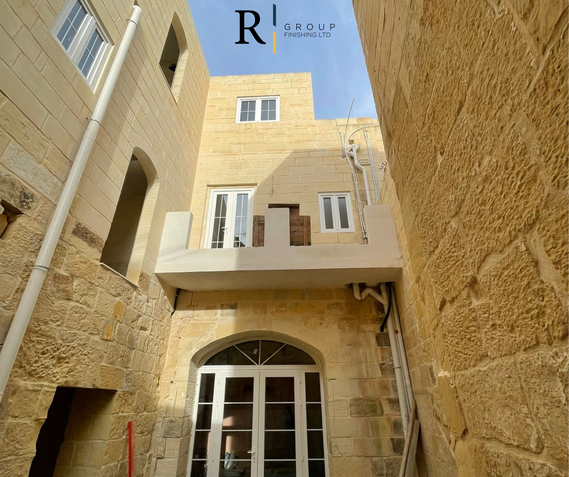 White aluminium arched door and windows fitted in traditional Maltese stone building by R Group